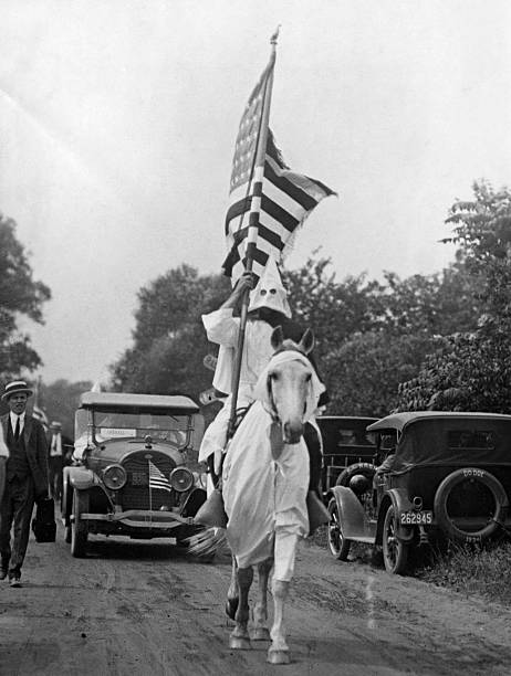 A klansmen on horseback, holding an American flag